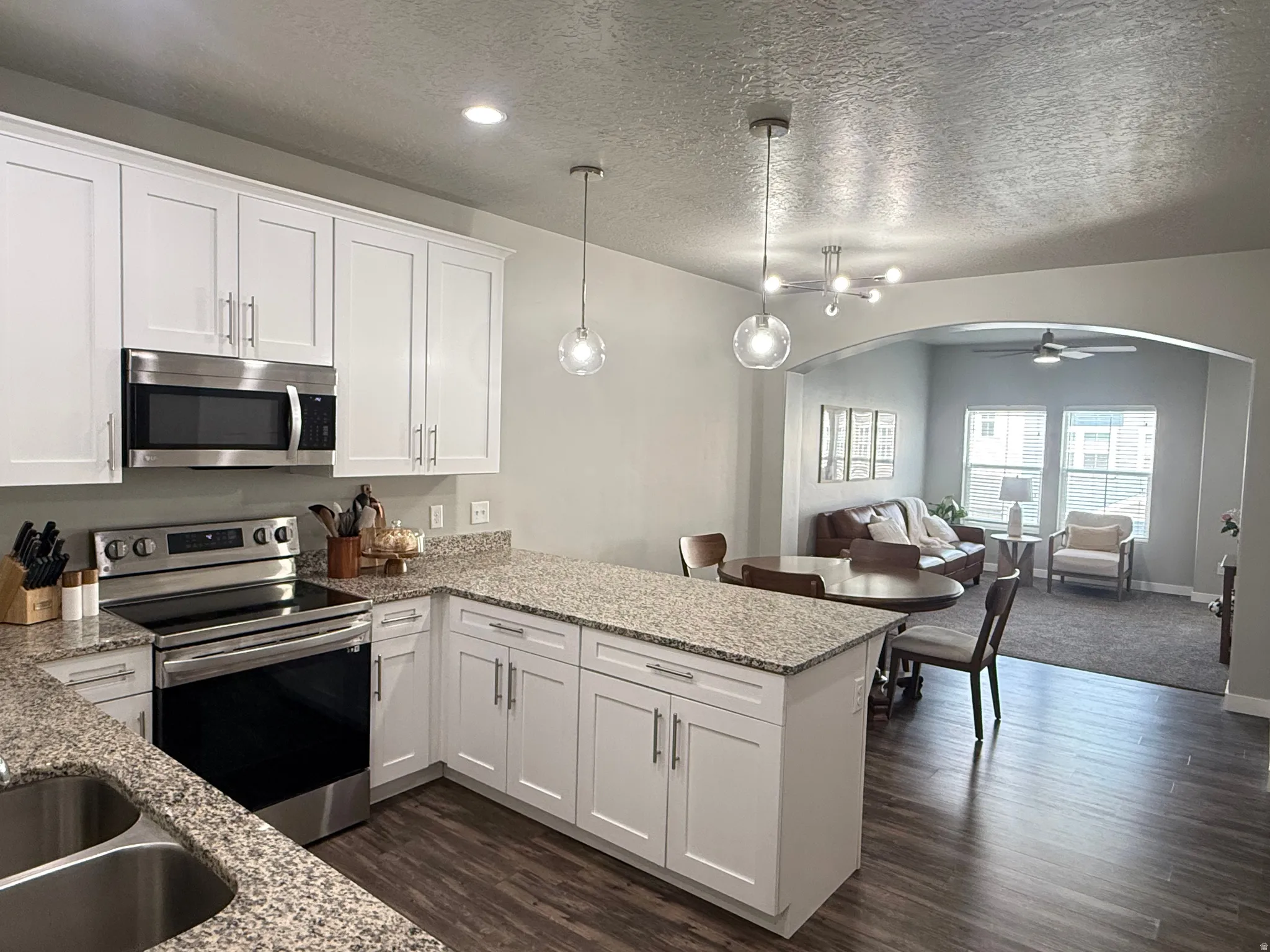 White shaker cabinetry, stainless steel appliances, granite countertops, wood-finish flooring, and recessed lighting