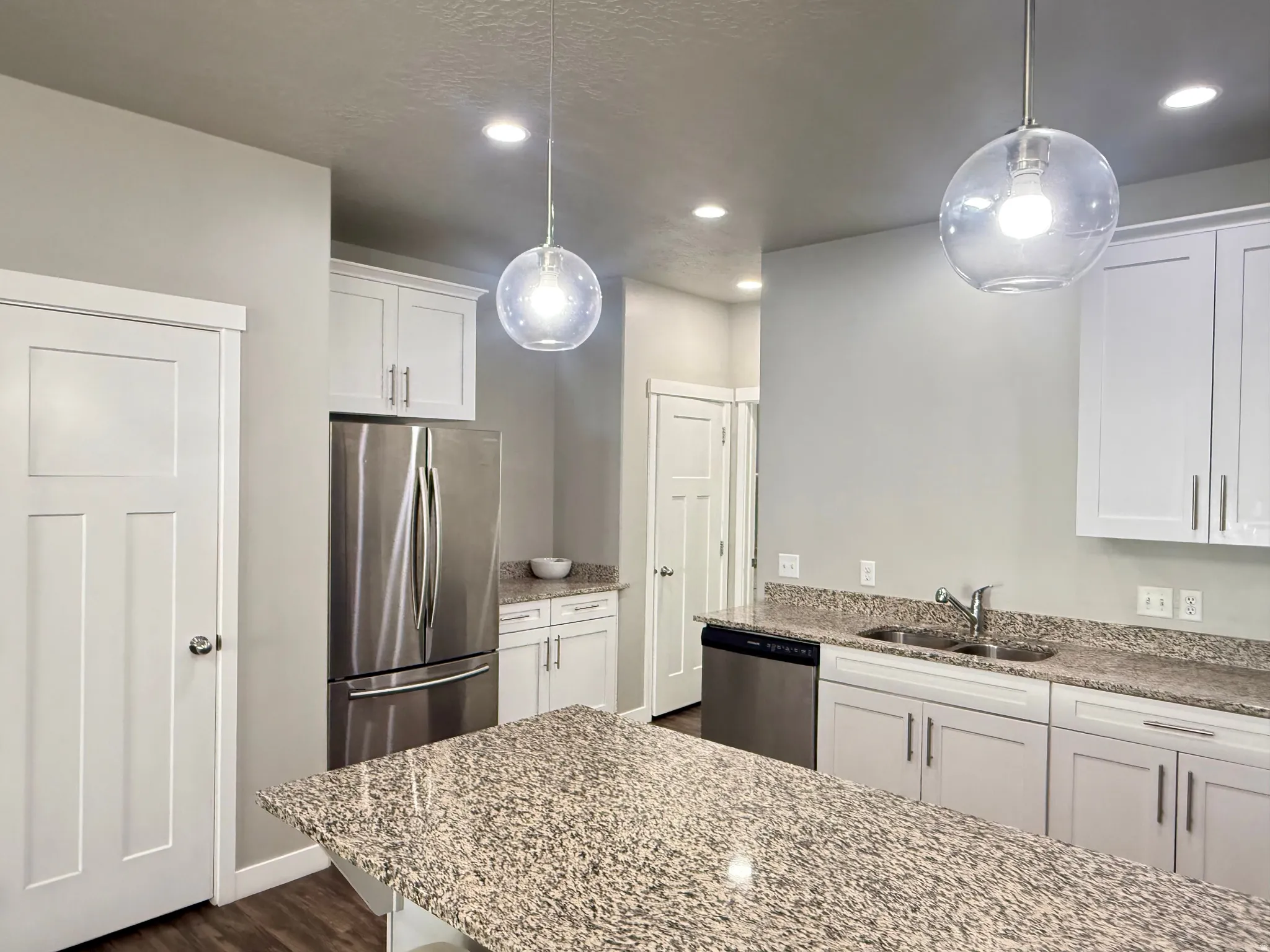 Kitchen featuring white shaker cabinetry, stainless steel appliances, speckled stone countertops, and recessed lighting