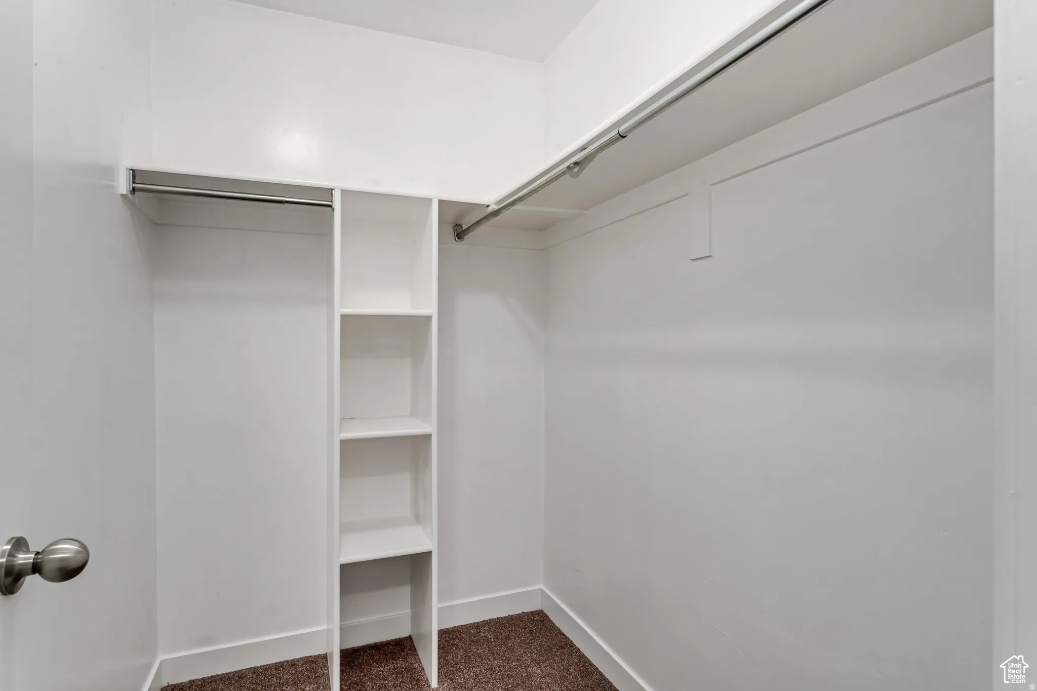 Built-in shelving unit, dual clothing rods, light-colored walls, and textured carpeting