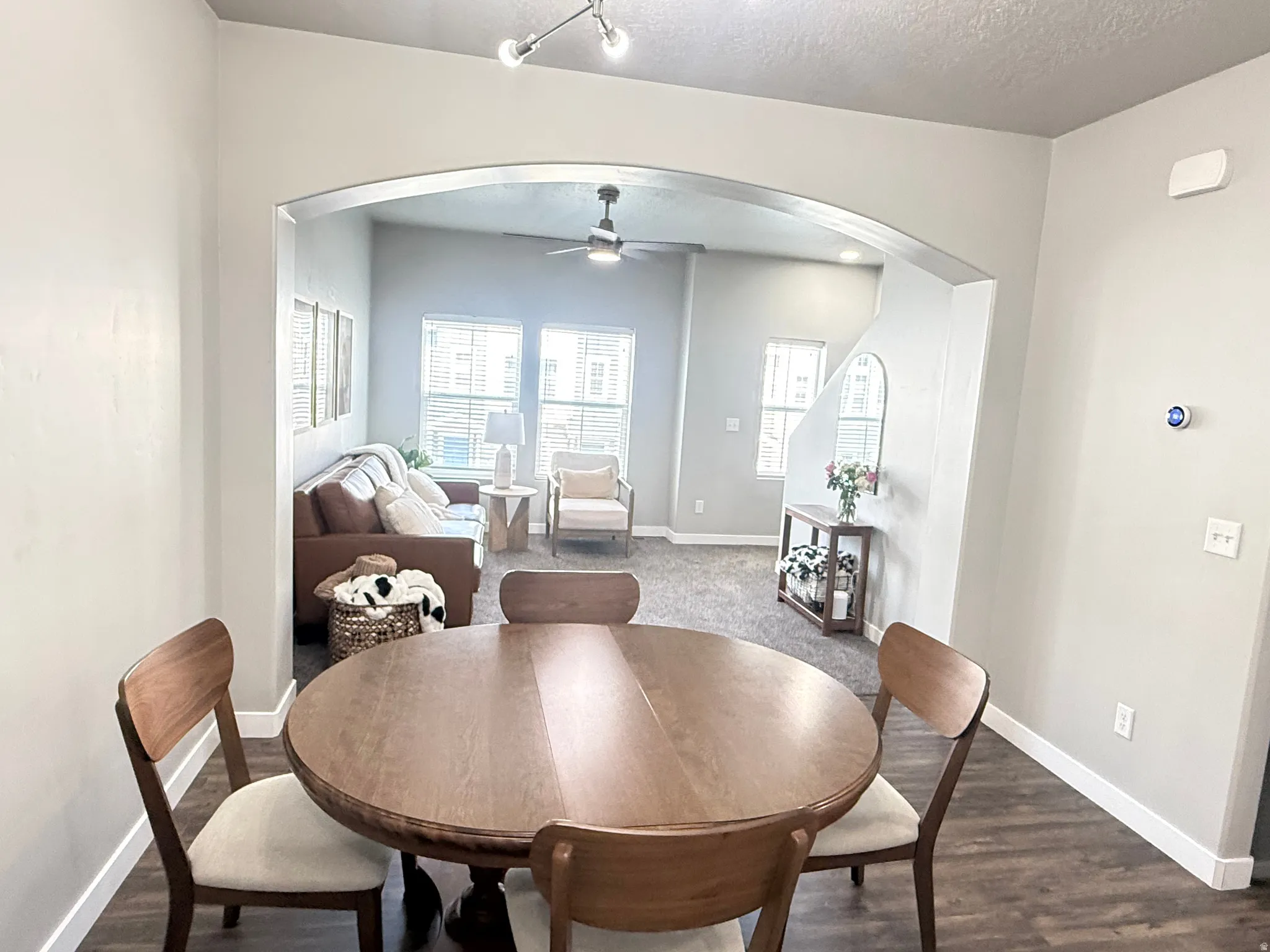 Archway opening to a living area with a ceiling fan and multiple windows