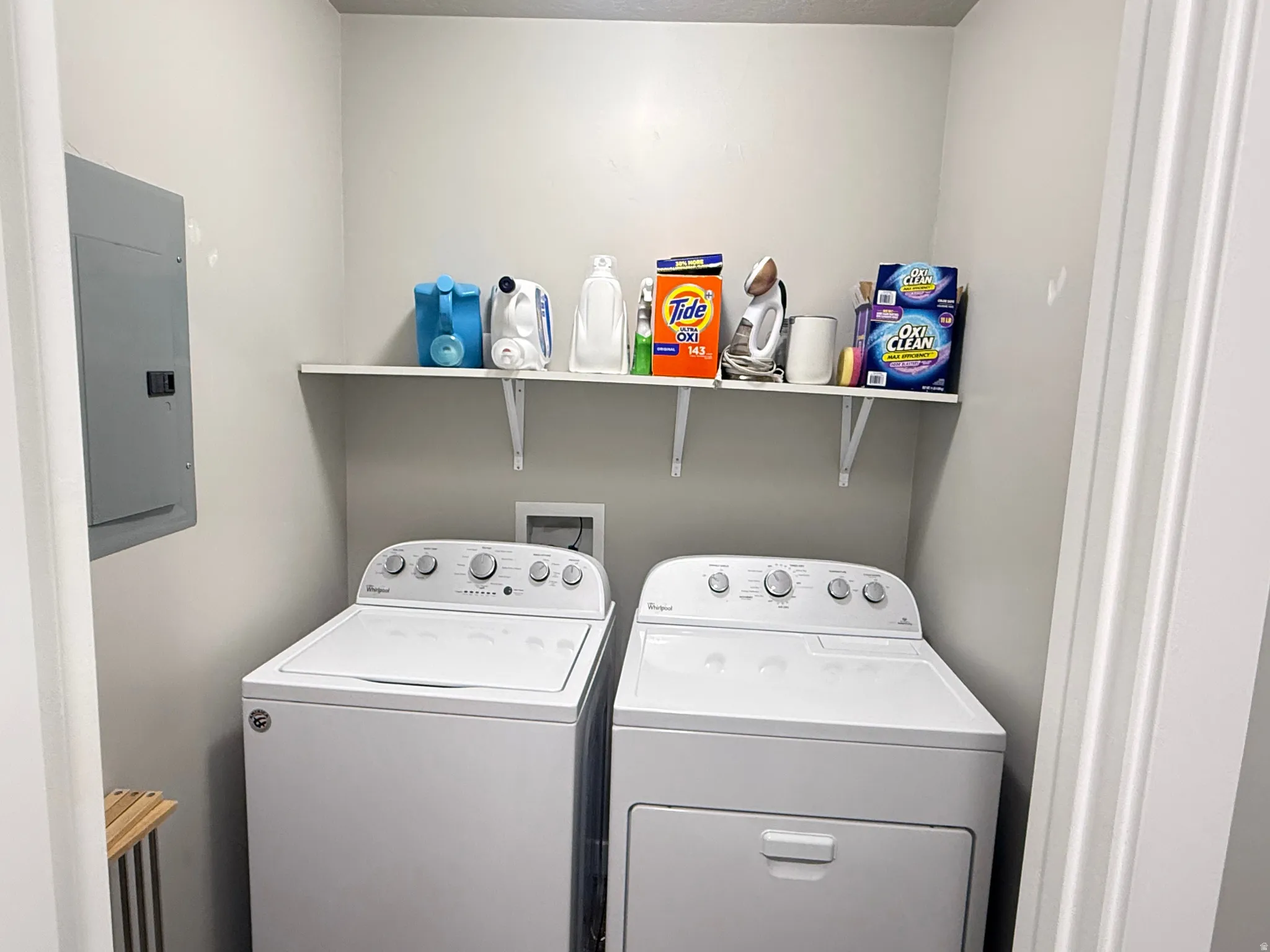 Built-in shelving, white washer, white dryer, and electrical panel
