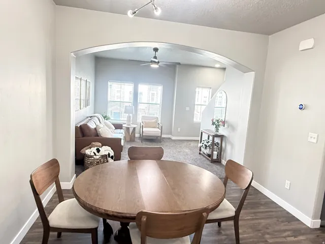Archway opening to a living area with a ceiling fan and multiple windows