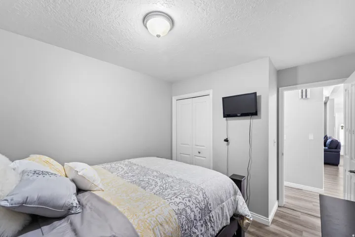 Neutral painted walls, ceiling-mounted light fixture, wood-finish flooring, and a white bi-fold closet