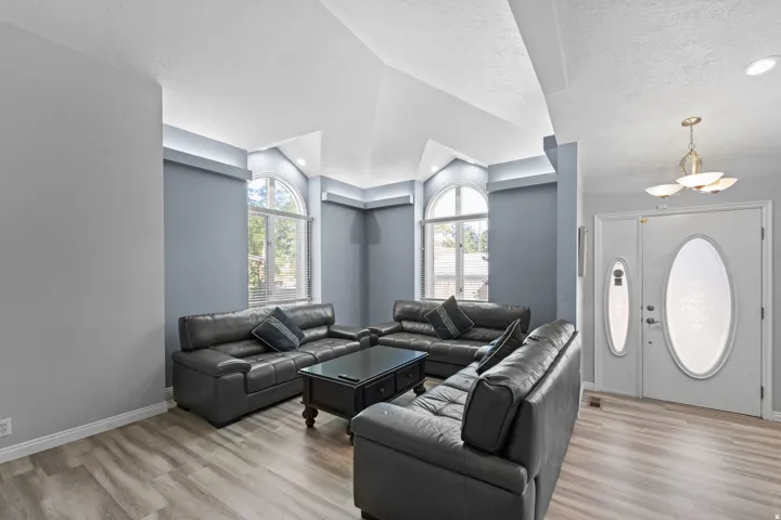 Vaulted ceilings, arched windows, wood-finish flooring, recessed lighting, and a chandelier
