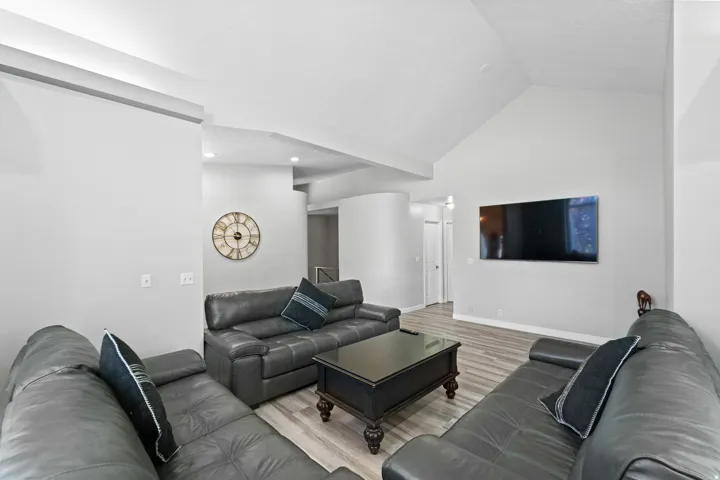 Vaulted ceiling, recessed lighting, wood-finish flooring, white trim, and white interior doors