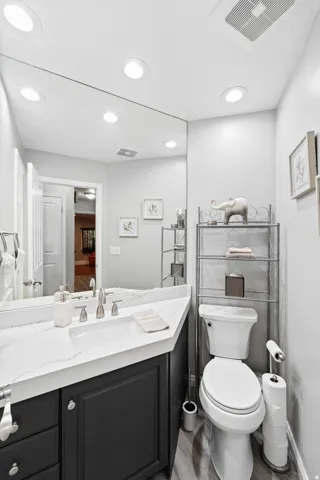 Vanity with white countertop, undermount sink, and dark cabinetry