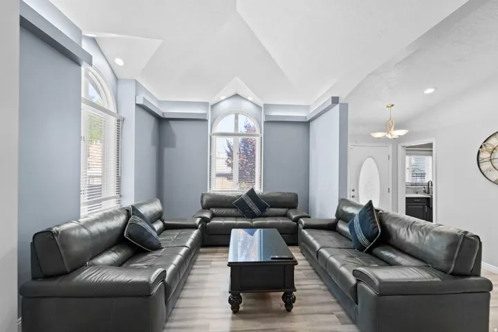 Vaulted ceiling with recessed lighting, arched windows, wood-finish flooring, and a decorative pendant light