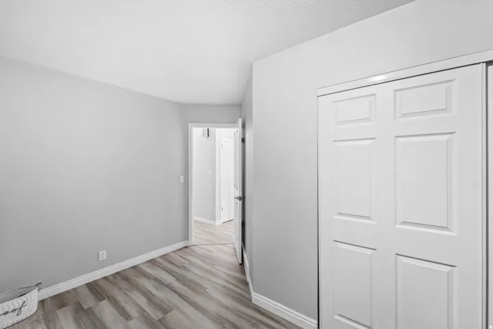 Wood-finish flooring with light gray walls, white baseboards, and a white paneled closet door