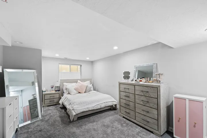 Recessed lighting illuminates the space, featuring light gray walls and a textured carpet