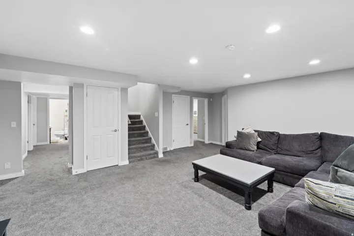 Spacious interior featuring neutral gray wall paint, gray carpet flooring, recessed ceiling lighting, and white paneled doors