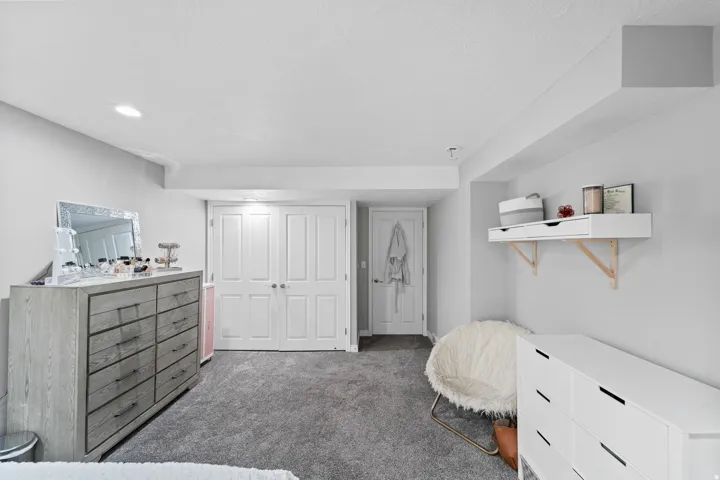 Recessed lighting, light gray wall paint, gray carpet, white double doors, and a built-in wall shelf