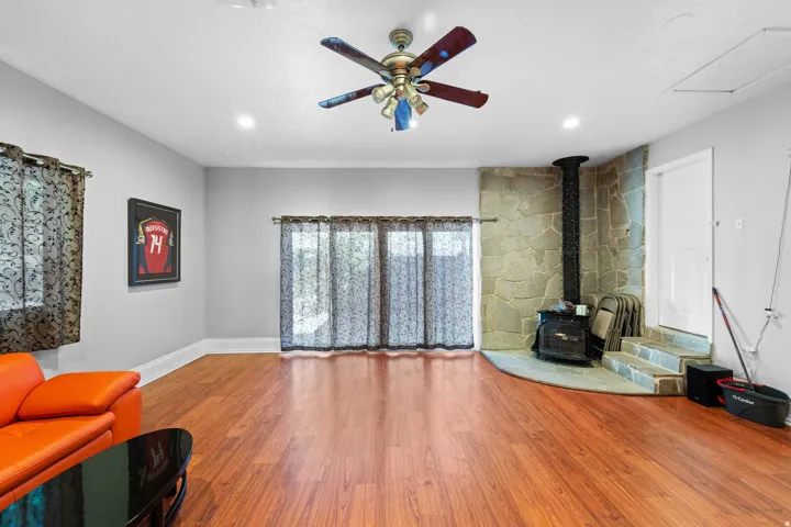 Wood-finish flooring throughout, featuring recessed lighting and a ceiling fan
