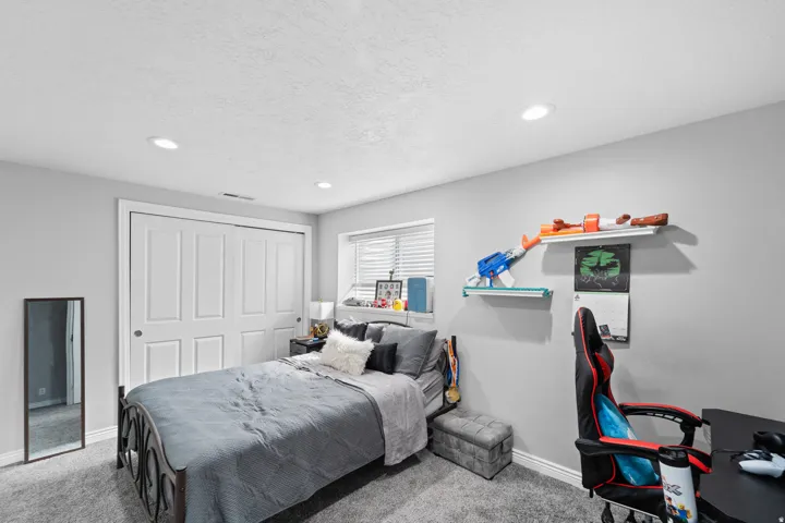 Recessed lighting, window with blinds, carpeted flooring, and a built-in closet with paneled bifold doors