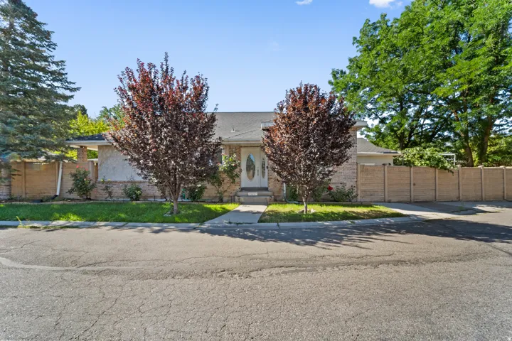 Exterior featuring a brick facade, a front entry door with an oval glass insert, a paved driveway, and mature landscaping