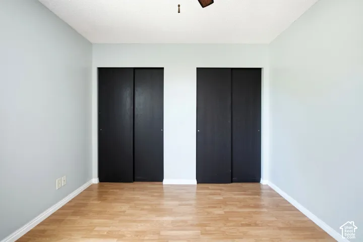 Master bedroom. Dual sliding closet doors, wood-finish flooring, and light blue wall paint