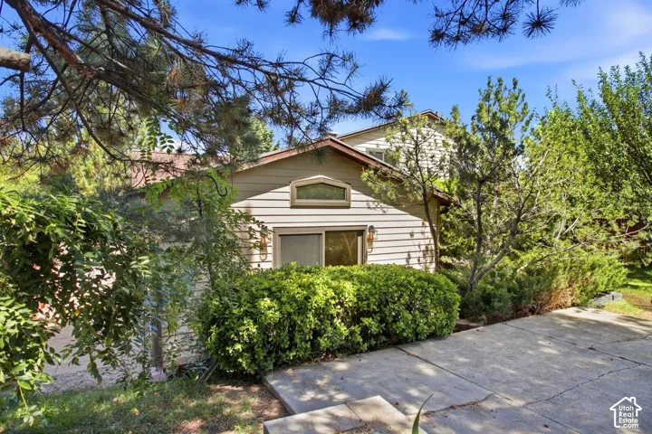 Siding exterior with a gable roof, integrated window, and established landscaping