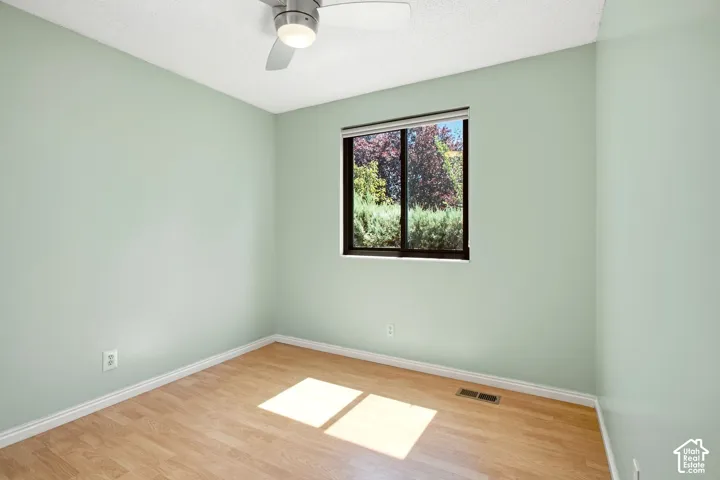 Bedroom 3. Recessed window with exterior greenery, wood-finish flooring, ceiling fan with integrated lighting, and light-toned wall finishes