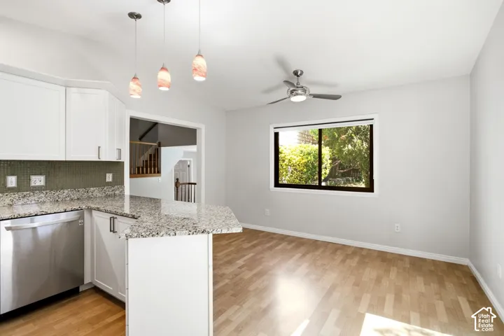White cabinetry with granite countertops, stainless steel dishwasher, wood-finish flooring, and a ceiling fan