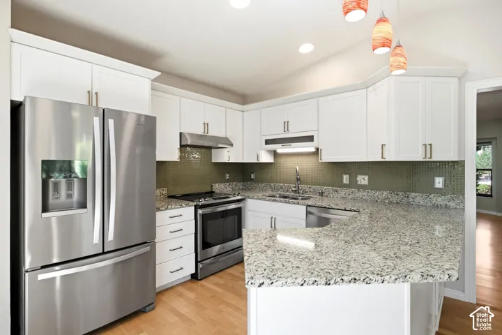Kitchen featuring white cabinetry, stainless steel appliances, speckled stone countertops, and a green tile backsplash