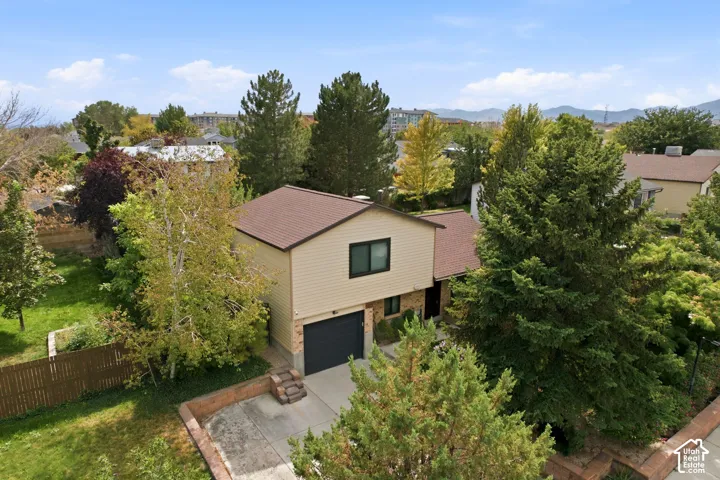 Two-story property with a brown shingle roof, beige siding, and brick accents