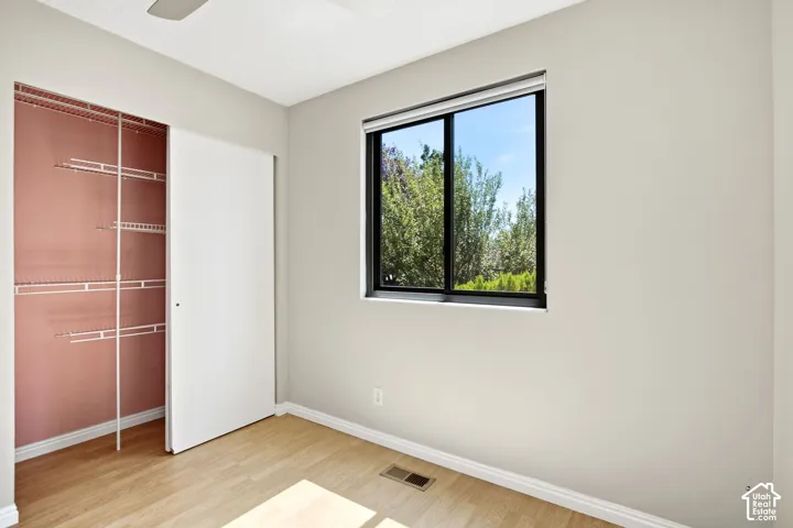 Bedroom 2. Wood-style flooring a ceiling fan, a sliding closet door, and a window with black trim
