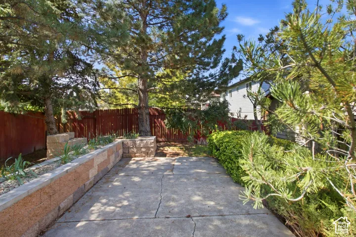 Concrete patio area featuring a block retaining wall with plantings