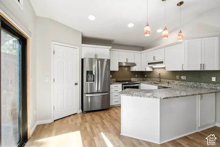 Kitchen featuring white cabinetry, stainless steel appliances, speckled countertops, a mosaic tile backsplash, and light wood-finish flooring