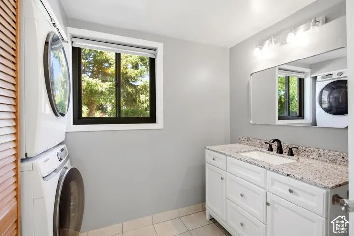 Half bath and laundry. White shaker-style vanity with a stone-finish countertop, integrated sink, and matte black faucet