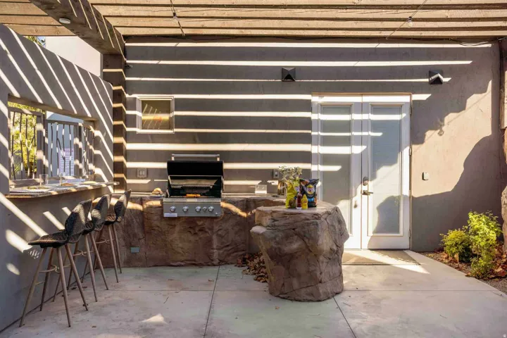 Outdoor kitchen featuring a built-in grill, stone-finish cabinetry, and an integrated bar