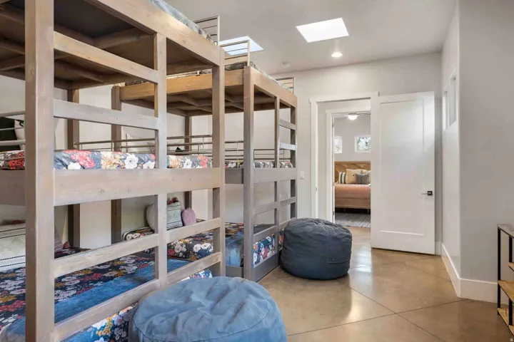 Room featuring multiple custom wood bunk beds, polished concrete flooring, a recessed ceiling light, and a skylight