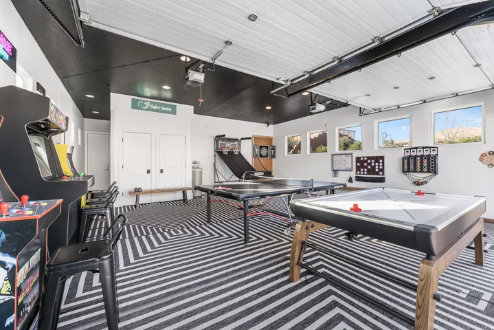 Spacious recreation room featuring a patterned floor, white walls, and multiple windows