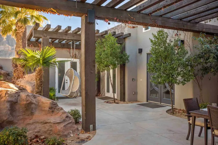 Expansive outdoor patio with a wood pergola, stucco exterior, and mature landscaping