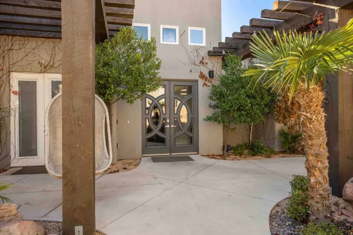 Contemporary entry with decorative double doors, square windows, and a wood pergola