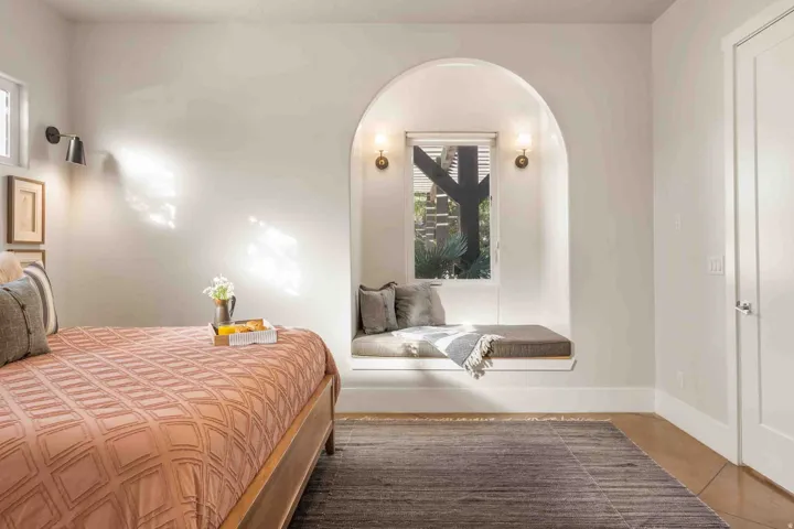 Recessed arched window nook with built-in bench seating, two sconce light fixtures, and wood-finish flooring