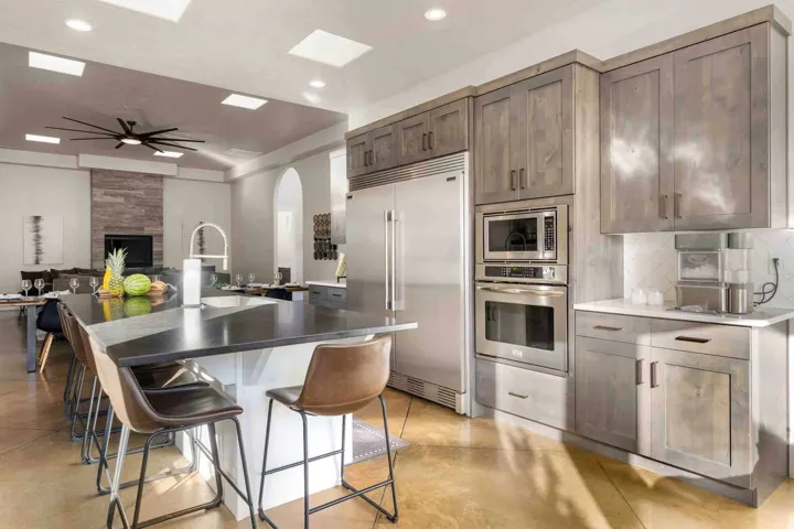 Spacious kitchen island with dark countertop, stainless steel appliances, wood-finish cabinetry, and recessed lighting