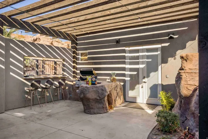 Outdoor patio featuring a wooden pergola, built-in bar, rock-finish counter, and double glass-paneled doors