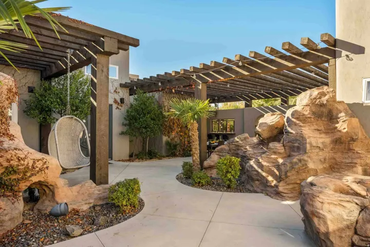 Expansive outdoor patio featuring multiple pergolas, integrated rock landscaping, and mature plantings
