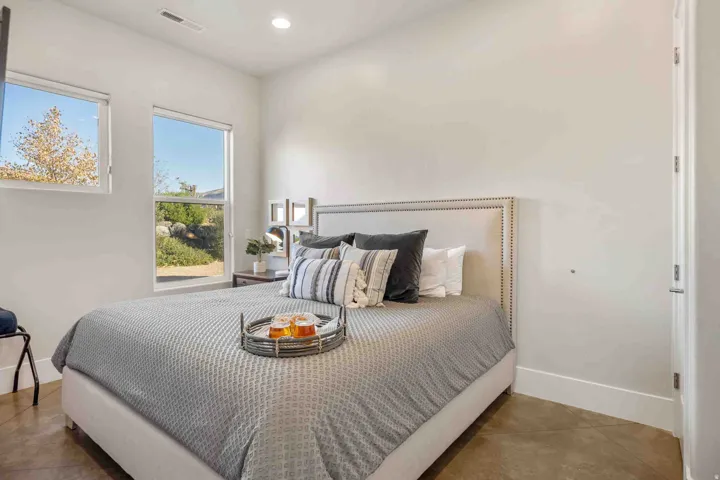 Polished concrete flooring, recessed lighting, two white-trimmed windows, and a solid core door