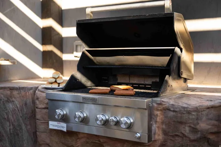 Built-in stainless steel grill with multiple burners, integrated into a stone-finish counter