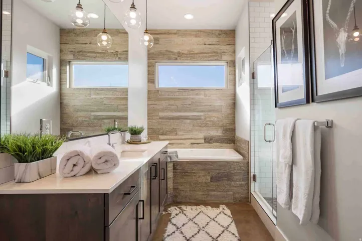 Double vanity with undermount sinks and quartz countertops, wood-finish accent wall, built-in soaking tub, and a glass-enclosed shower