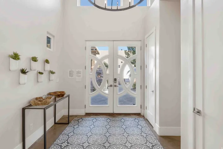 Double entry doors with decorative glass panels, transom window, and chandelier