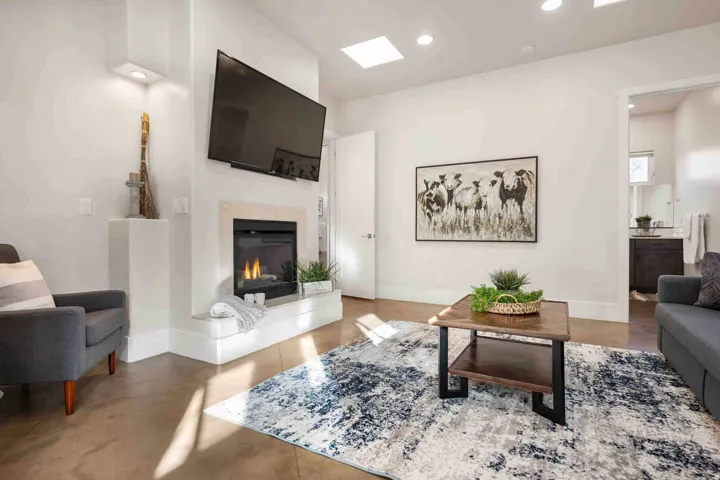 Living area featuring a built-in fireplace, wall-mounted television, two skylights, recessed lighting, and a doorway opening to an additional room