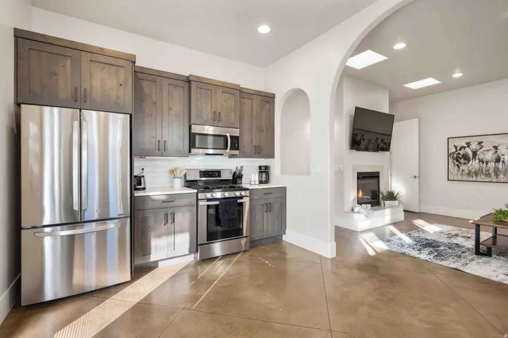 Contemporary kitchen featuring stainless steel appliances, wood-finish cabinetry, and a white tile backsplash