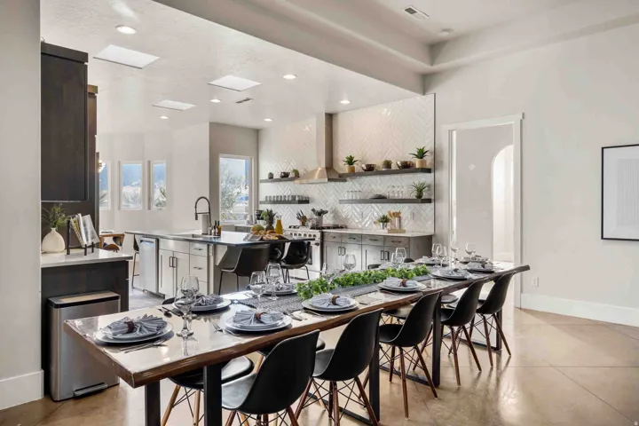 Spacious kitchen and dining area featuring recessed lighting, skylights, a center island with a sink, and a herringbone tile backsplash