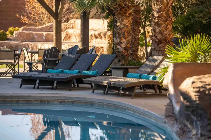 Resort-style pool area featuring a curved swimming pool, extensive concrete decking, and mature palm trees