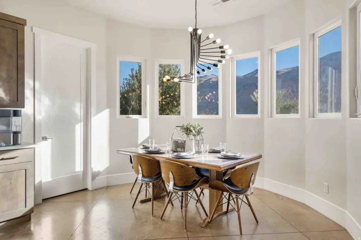 Curved wall with five vertical windows, contemporary chandelier, light-toned flooring, white baseboards, and built-in cabinetry