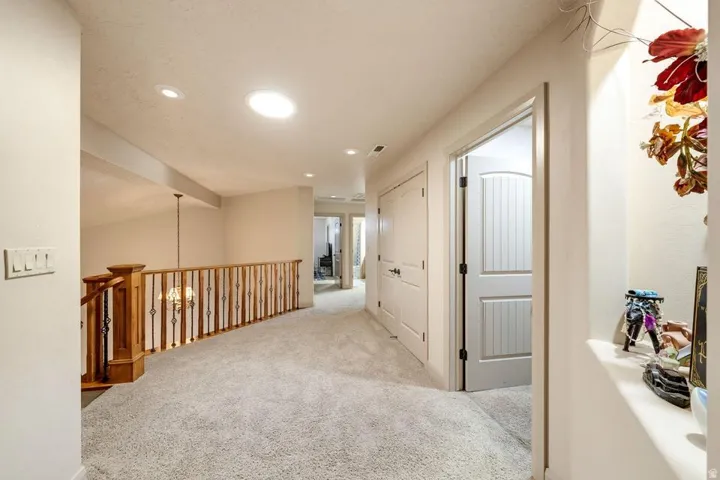 Carpeted landing featuring a wood and wrought iron railing, recessed lighting, and a built-in wall niche