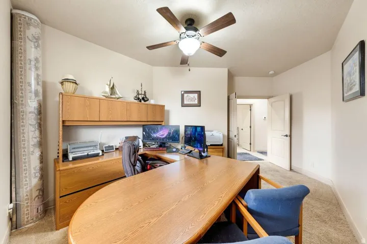 Vaulted ceiling with a ceiling fan light fixture, light-colored carpeting, and light-toned wall paint