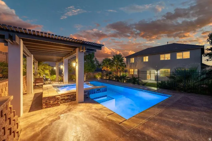 Outdoor entertaining area featuring a rectangular swimming pool, integrated spa, and a covered pergola