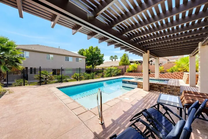 Outdoor living area featuring a pergola, a rectangular swimming pool, and an integrated spa